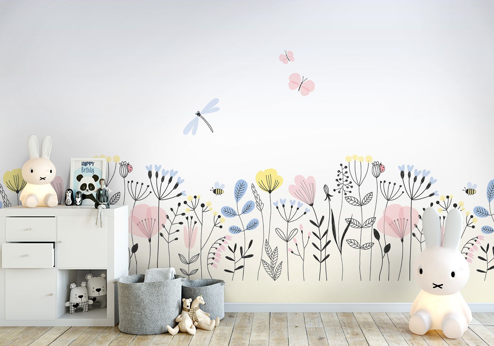 Milieubild mit  Kinderzimmer mit weißer Kommode, Hasenlampe, Spielzeug, grauen Körben auf dem Boden und einer Wandverkleidung mit folgendem Motiv: Illustration einer Wiese mit Blumen, Schmetterlingen und einer Libelle auf einem hellen Hintergrund.