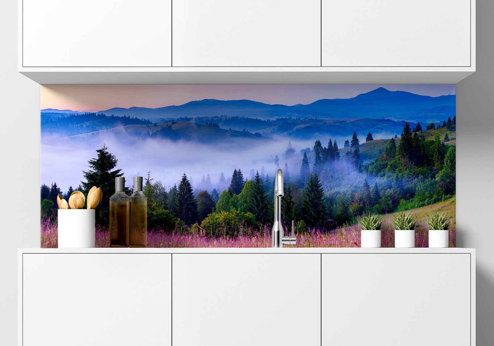 Küchenrückwand -  Berglandschaft mit Nebel im Abendrot Küche  mit weißen Hängeschränken, Spüle, Gewürzständer, Topfpflanzen und Küchenrückwand mit folgendem Motiv: Nebelverhangene Berglandschaft bei Sonnenaufgang mit lila Blumenwiese im Vordergrund und dichten Nadelwäldern im Tal.