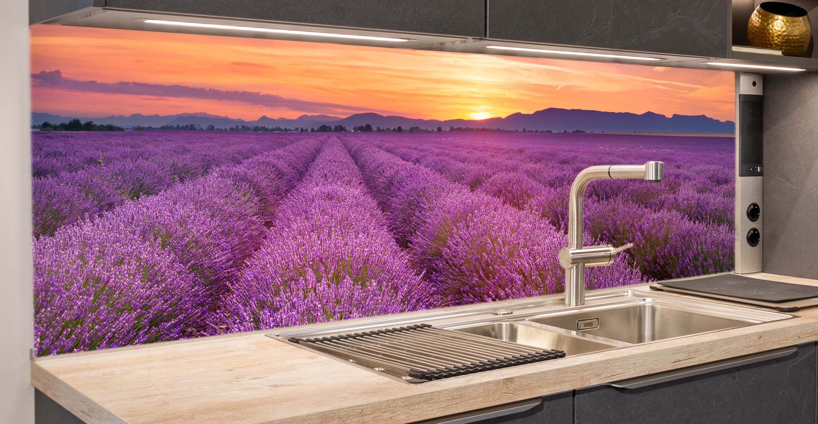 Zeitlose, edle Küchenzeile mit Edelstahlspüle, Holzarbeitsplatte und bedruckter Glasrückwand, das ein Lavendelfeld bei Sonnenuntergang zeigt.