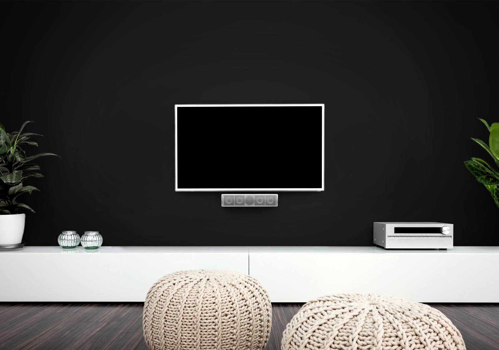 Milieubild mit Wohnzimmer mit TV,  weißer Kommode, grauen Sitzkissen, Zimmerpflanzen und einer Wandverkleidung mit folgendem Motiv: Einfarbig schwarzes Bild, keine sichtbaren Details oder Muster.