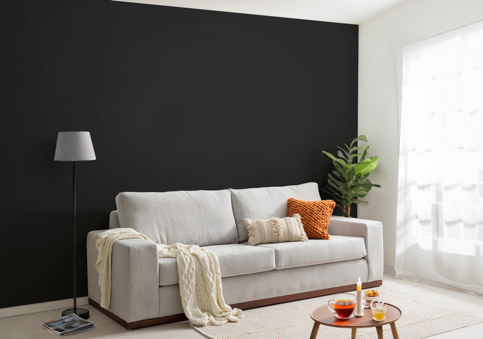 Milieubild mit Wohnzimmer mit grauer Couch, Zierkissen, Decke, Beistelltisch, Lampe, Pflanze und einer Wandverkleidung mit folgendem Motiv: Einfarbig schwarzes Bild, keine sichtbaren Details oder Muster.