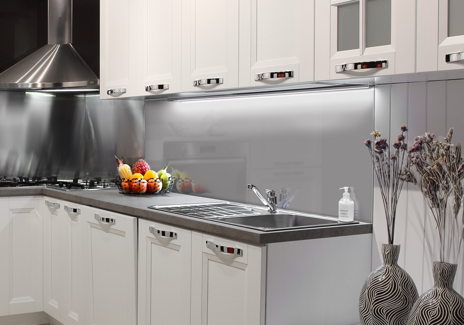 RW-K-P_Unifarben-02.jpg Weiße Küche mit Edelstahl-Dunstabzugshaube, Spüle, Obstschale und zwei Vasen mit Dekozweigen. Es ist eine Küchenrückwand mit folgendem Motiv verbaut: Einfarbig graues Bild, keine sichtbaren Details oder Muster.