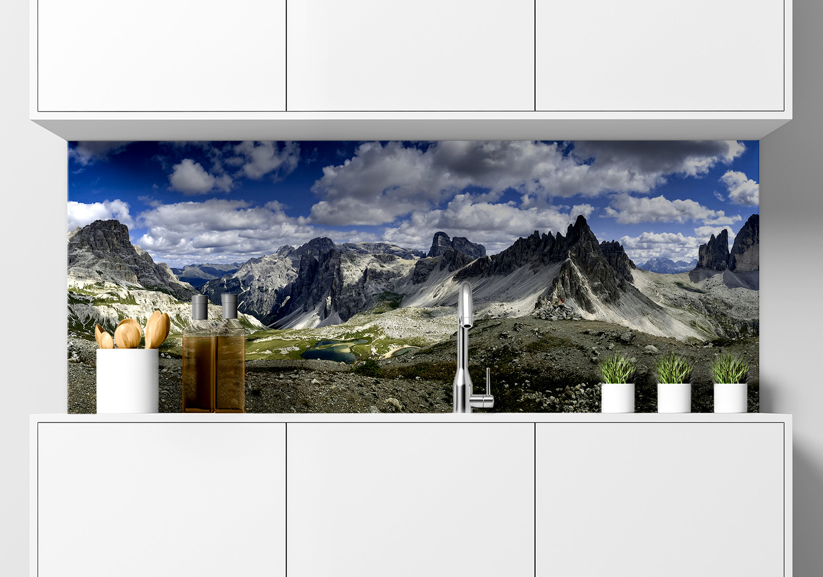 Küchenrückwand - Dolomiten Berge Küche  mit weißen Hängeschränken, Spüle, Gewürzständer, Topfpflanzen und Küchenrückwand mit folgendem Motiv: Panorama der zerklüfteten Gipfel der Dolomiten unter einem Himmel mit flauschigen Wolken, mit einem kleinen See in einem Tal.