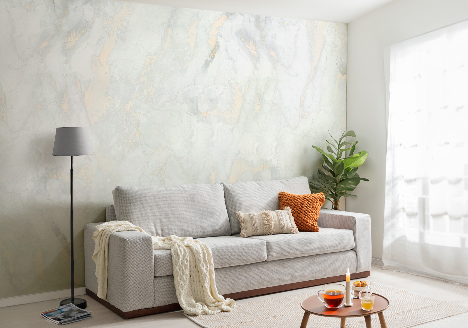 Milieubild mit Wohnzimmer mit grauer Couch, Zierkissen, Decke, Beistelltisch, Lampe, Pflanze und einer Wandverkleidung mit folgendem Motiv: Weißer Marmor mit grauen und goldenen Adern, abstrakte Textur.