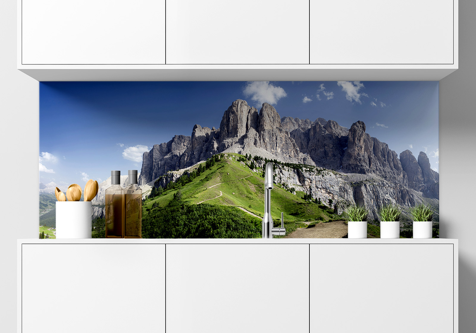 Küchenrückwand - Dolomiten Berge Küche  mit weißen Hängeschränken, Spüle mit Armatur, Gewürzständer und kleinen Topfpflanzen auf der Arbeitsfläche. Es ist eine Küchenrückwand mit folgendem Motiv verbaut: Panorama der Dolomiten mit grünen Hängen und felsigen Gipfeln unter blauem Himmel.