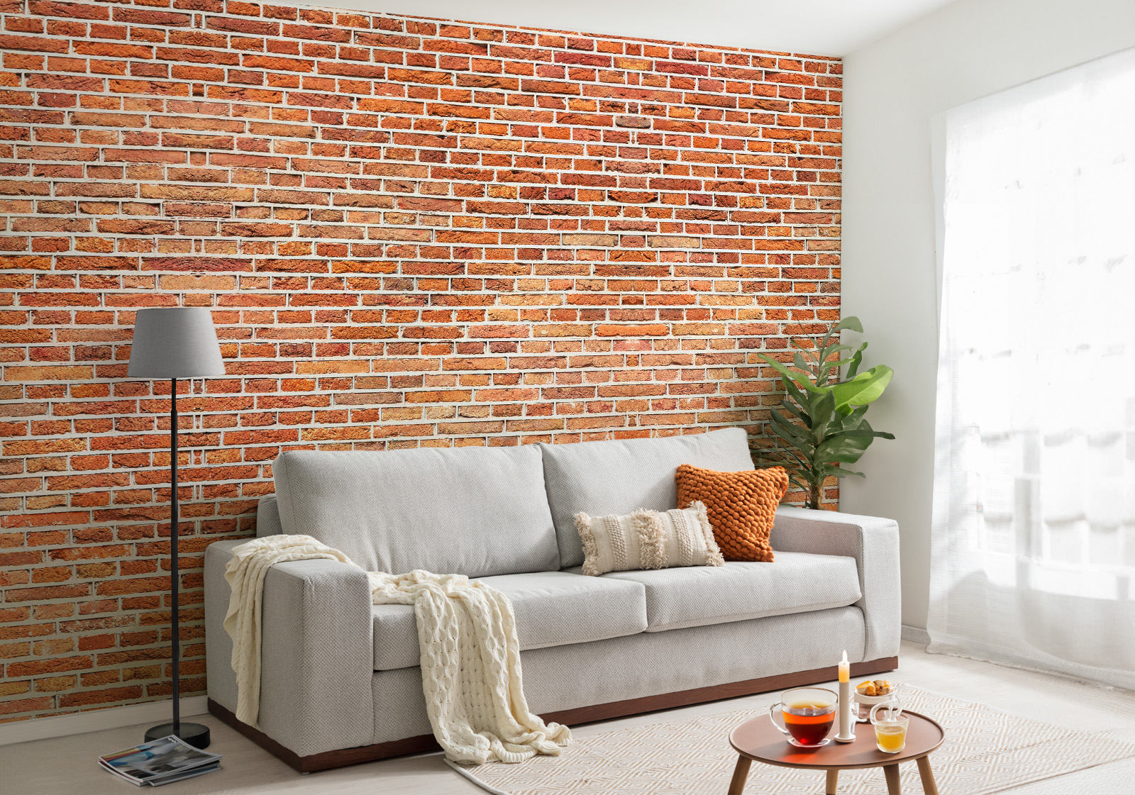 Milieubild mit Wohnzimmer mit grauer Couch, Zierkissen, Decke, Beistelltisch, Lampe, Pflanze und einer Wandverkleidung mit folgendem Motiv: Rote Backsteinmauer mit grauen Fugen, regelmäßiges Muster, Textur.