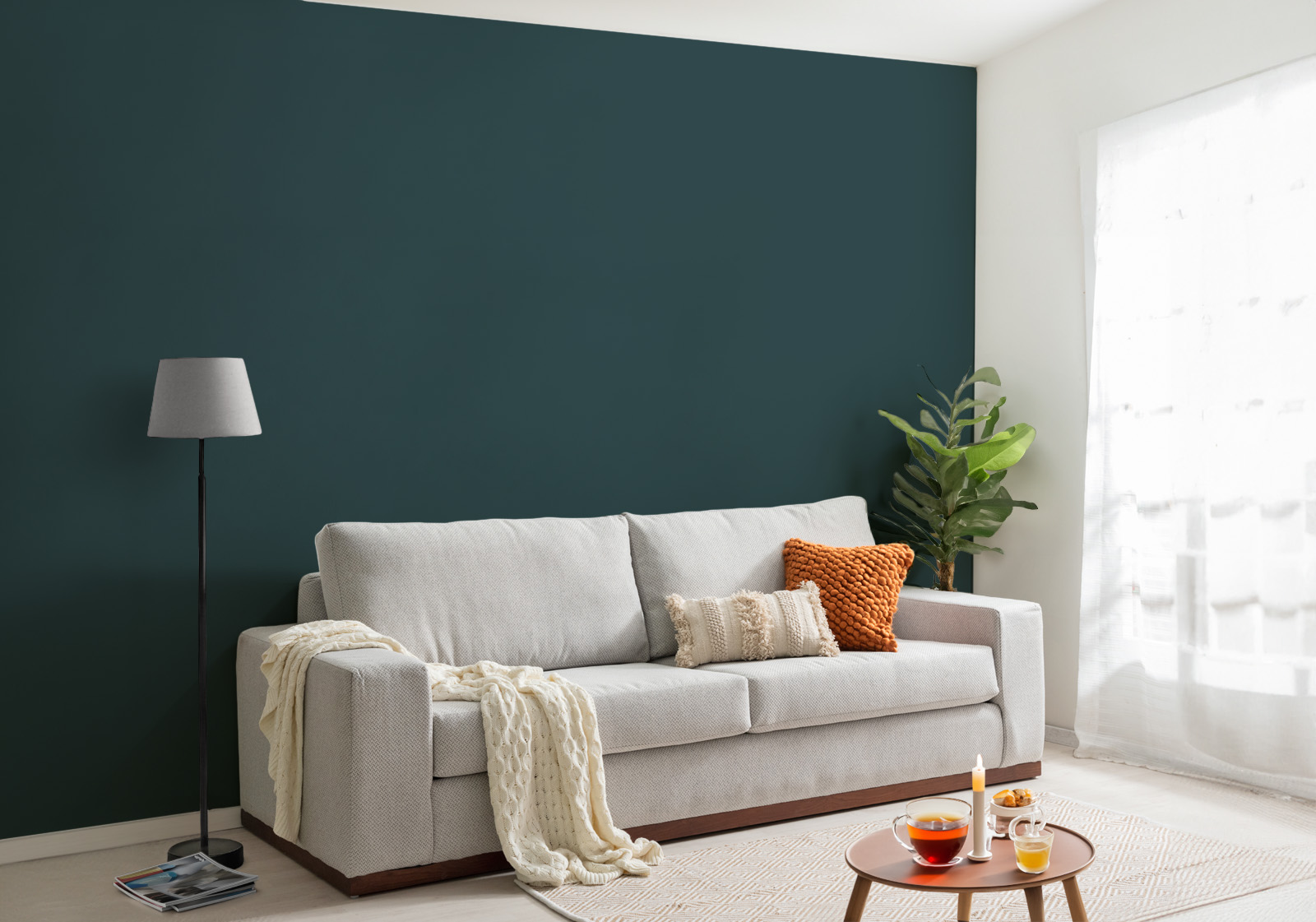 Milieubild mit Wohnzimmer mit grauer Couch, Zierkissen, Decke, Beistelltisch, Lampe, Pflanze und einer Wandverkleidung mit folgendem Motiv: Einfarbig dunkelgrünes Bild, keine sichtbaren Details oder Muster.