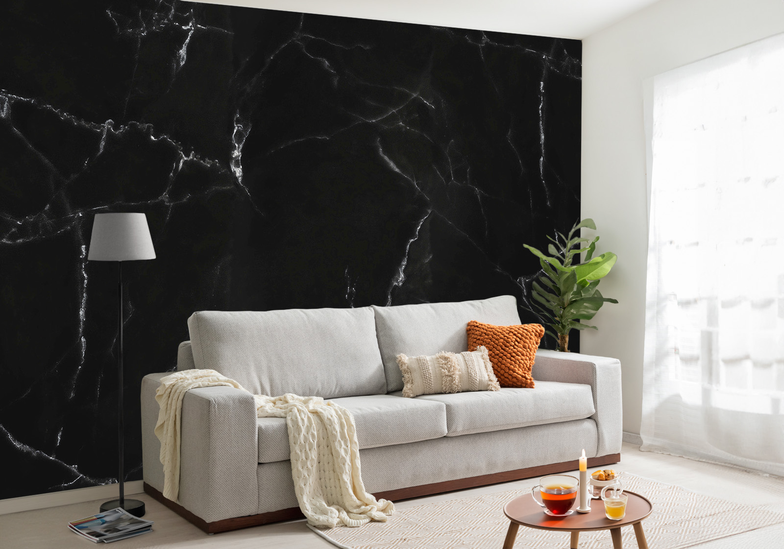 Milieubild mit Wohnzimmer mit grauer Couch, Zierkissen, Decke, Beistelltisch, Lampe, Pflanze und einer Wandverkleidung mit folgendem Motiv: Schwarzer Marmor mit weißen Adern, abstrakte Textur, dunkle und elegante Oberfläche.