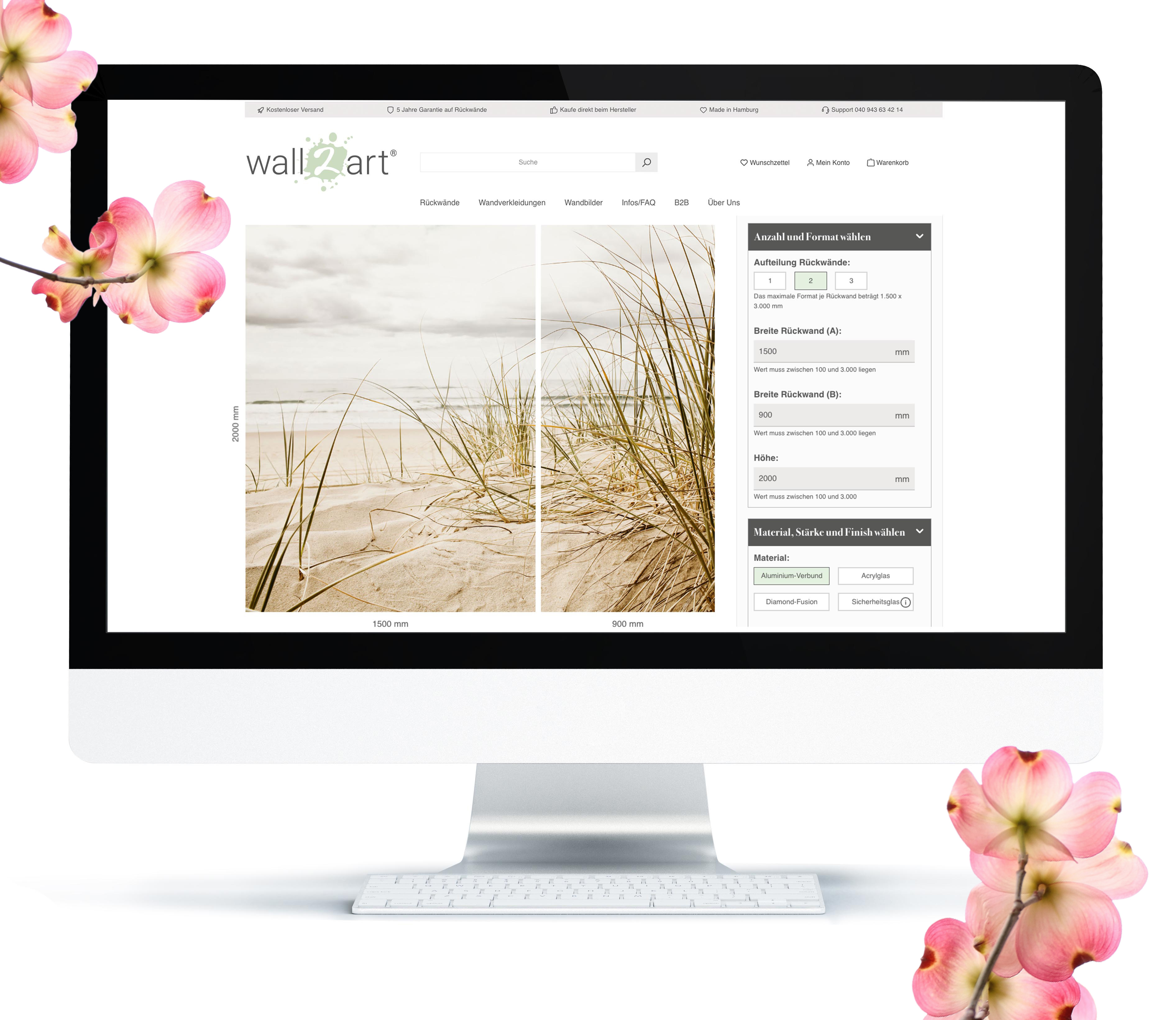 Computerbildschirm mit der Webseite wall2art, auf der ein Strandbild zur Wandgestaltung konfiguriert wird. Im Hintergrund sind Kirschblüten zu sehen.