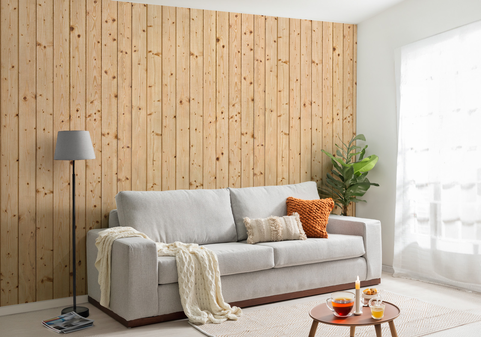 Milieubild mit Wohnzimmer mit grauer Couch, Zierkissen, Decke, Beistelltisch, Lampe, Pflanze und einer Wandverkleidung mit folgendem Motiv: Helle Holzplanken mit sichtbarer Maserung und Astlöchern, vertikal angeordnet.