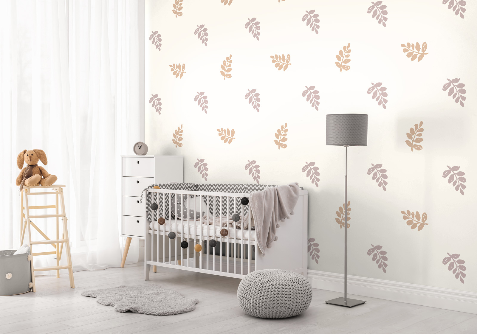 Milieubild mit Kinderzimmer mit weißem Gitterbett, Stehlampe, Holzregal, grauem Teppich, Strickhocker und einer Wandverkleidung mit folgendem Motiv: Muster mit stilisierten, hellbraunen Blättern auf einem hellen Hintergrund.