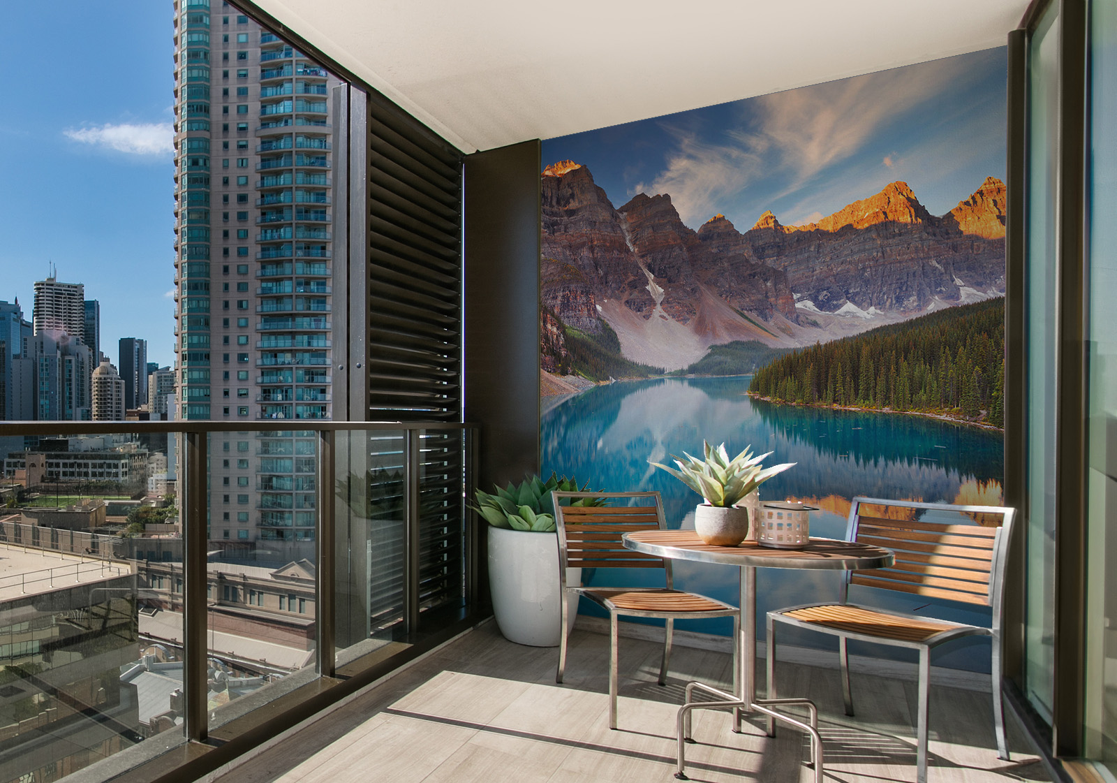 Milieubild mit Balkon mit Tisch und Stühlen, mit  Blick auf die Stad  und einer Wandverkleidung mit folgendem Motiv: Spiegelung der schneebedeckten Berge im türkisfarbenen Wasser des Moraine Lake in Kanada, umgeben von dichten Nadelbäumen.