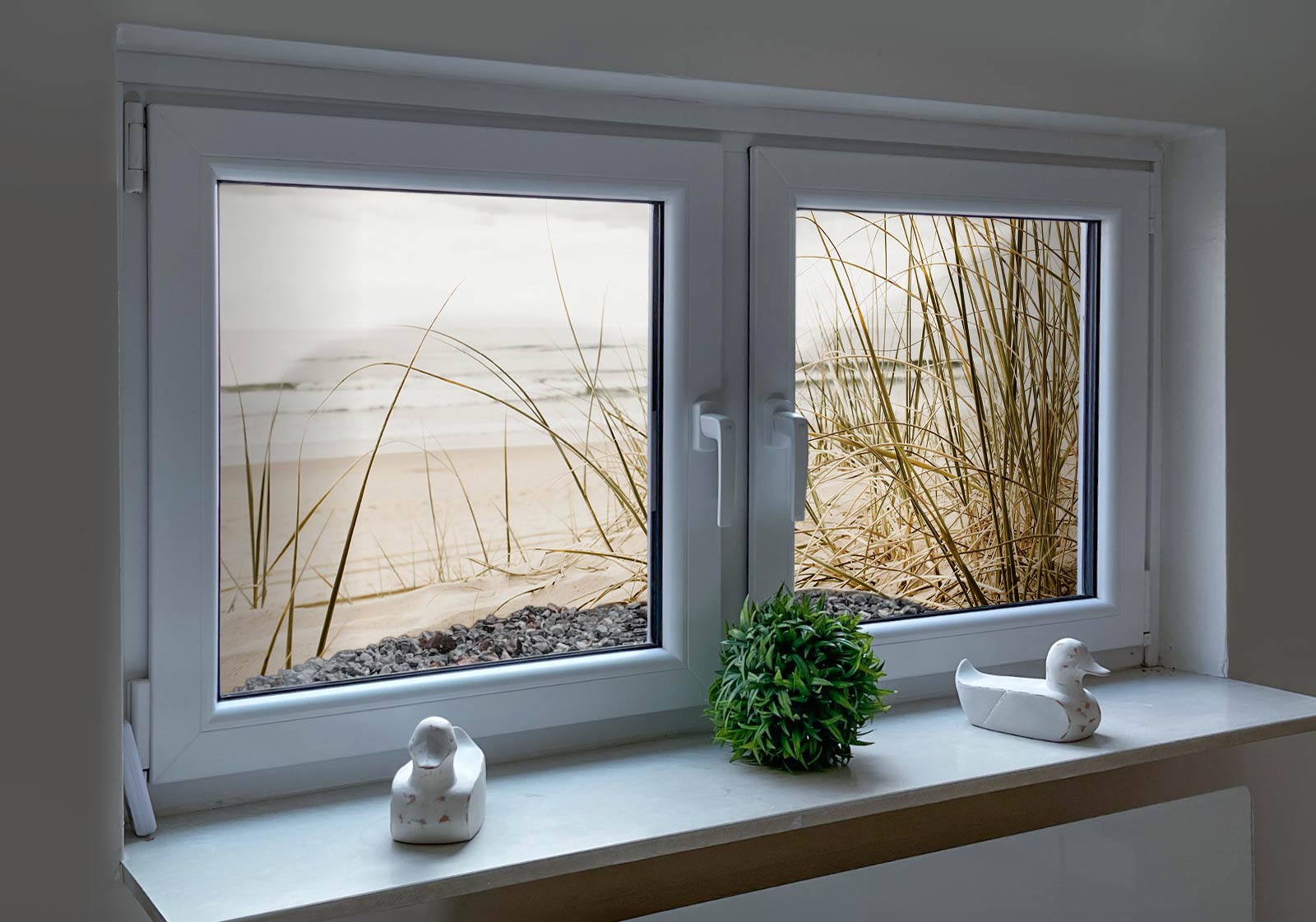 Nachher Zwei Fenster mit einem Lichtschacht und Topfpflanze und zwei Entenfiguren auf der Fensterban. Im Lichtschacht ist ein Lichtschachtbild platziert mit folgendem Motiv: Strandhafer im Sand, Meer im Hintergrund, bewölkter Himmel.