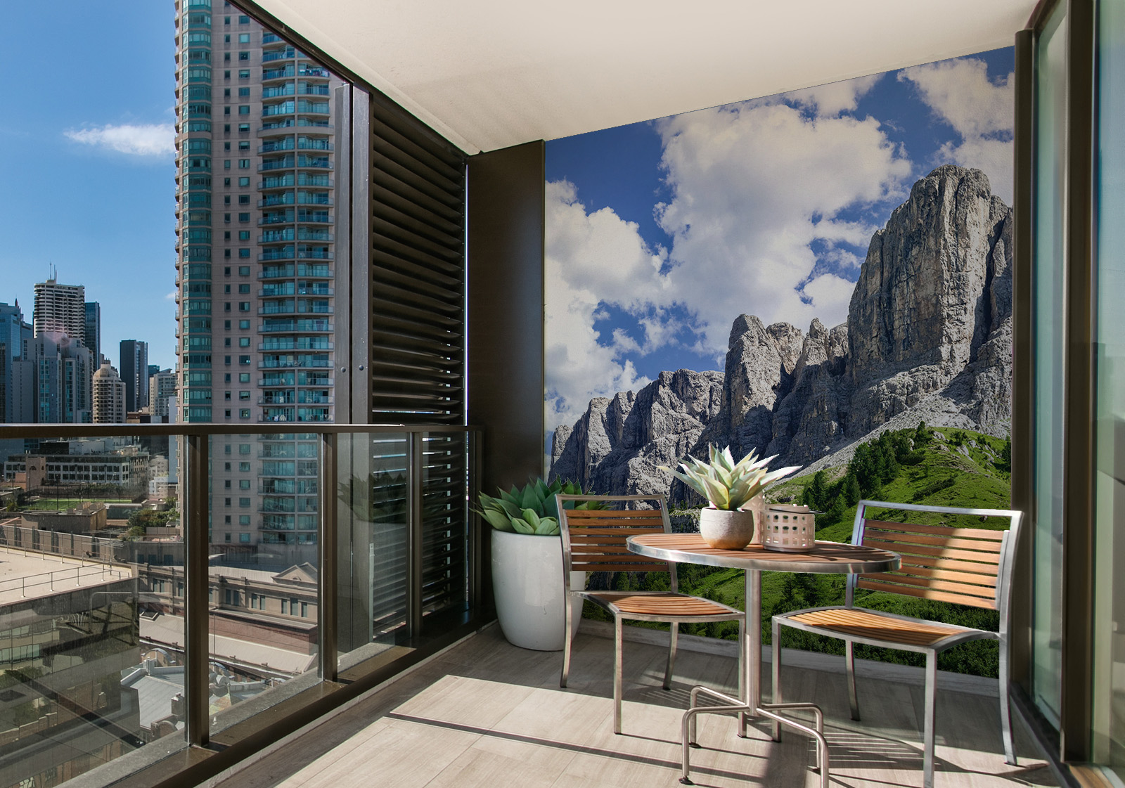 Wandverkleidung für den Außenbereich mit Motiv Dolomiten Berge Milieubild mit Balkon mit Tisch und Stühlen, mit  Blick auf die Stad  und einer Wandverkleidung mit folgendem Motiv: Panorama der Dolomiten mit grünen Hängen und felsigen Gipfeln unter blauem Himmel.