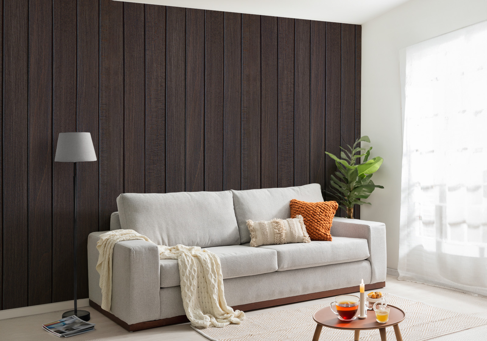Milieubild mit Wohnzimmer mit grauer Couch, Zierkissen, Decke, Beistelltisch, Lampe, Pflanze und einer Wandverkleidung mit folgendem Motiv: Dunkelbraune Holzpaneele mit feiner Maserung, vertikal angeordnet.